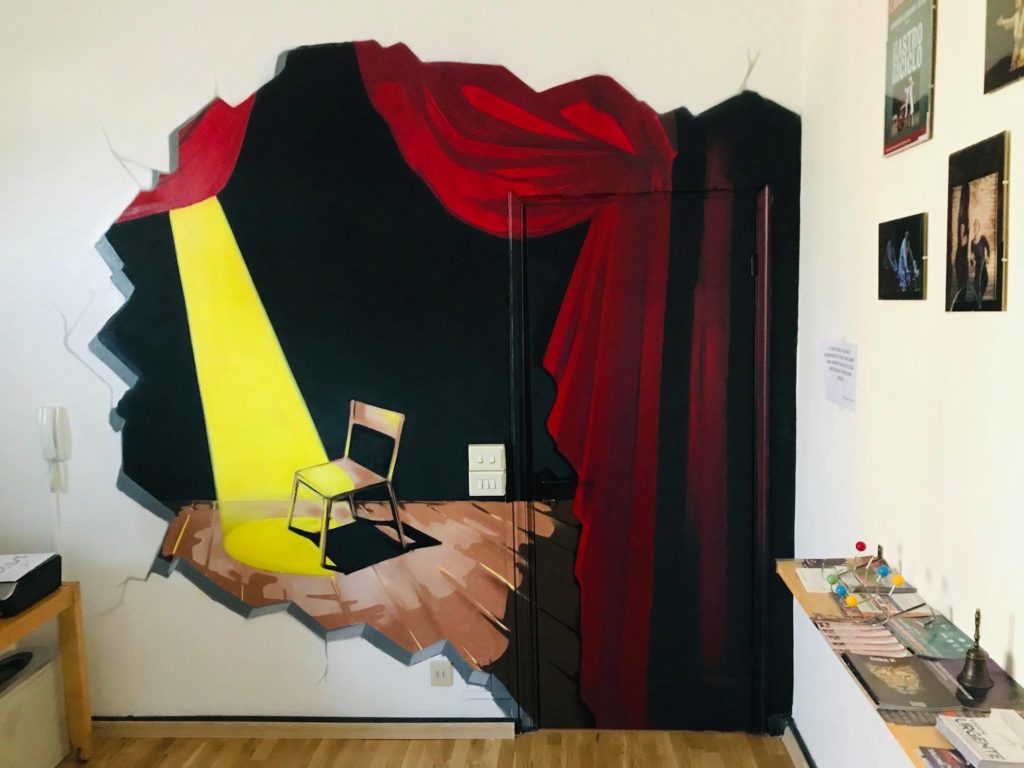 Murales trompe-l'œil con tenda rossa dipinta su una parete interna realizzato dall'artista Mario Jin