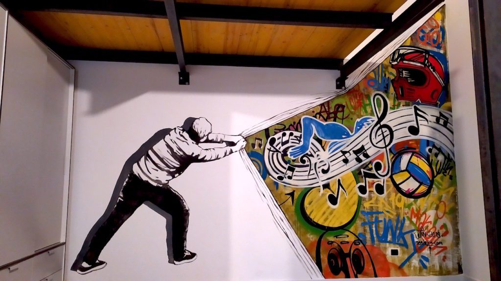 Murales con una figura in bianco e nero che rivela un'esplosione di note musicali e elementi sportivi
